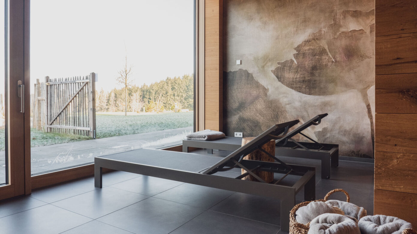 Entspannungsraum mit Liegen, Blick nach draußen, modernes Interieur, Natur, Ruhe, Wellness.