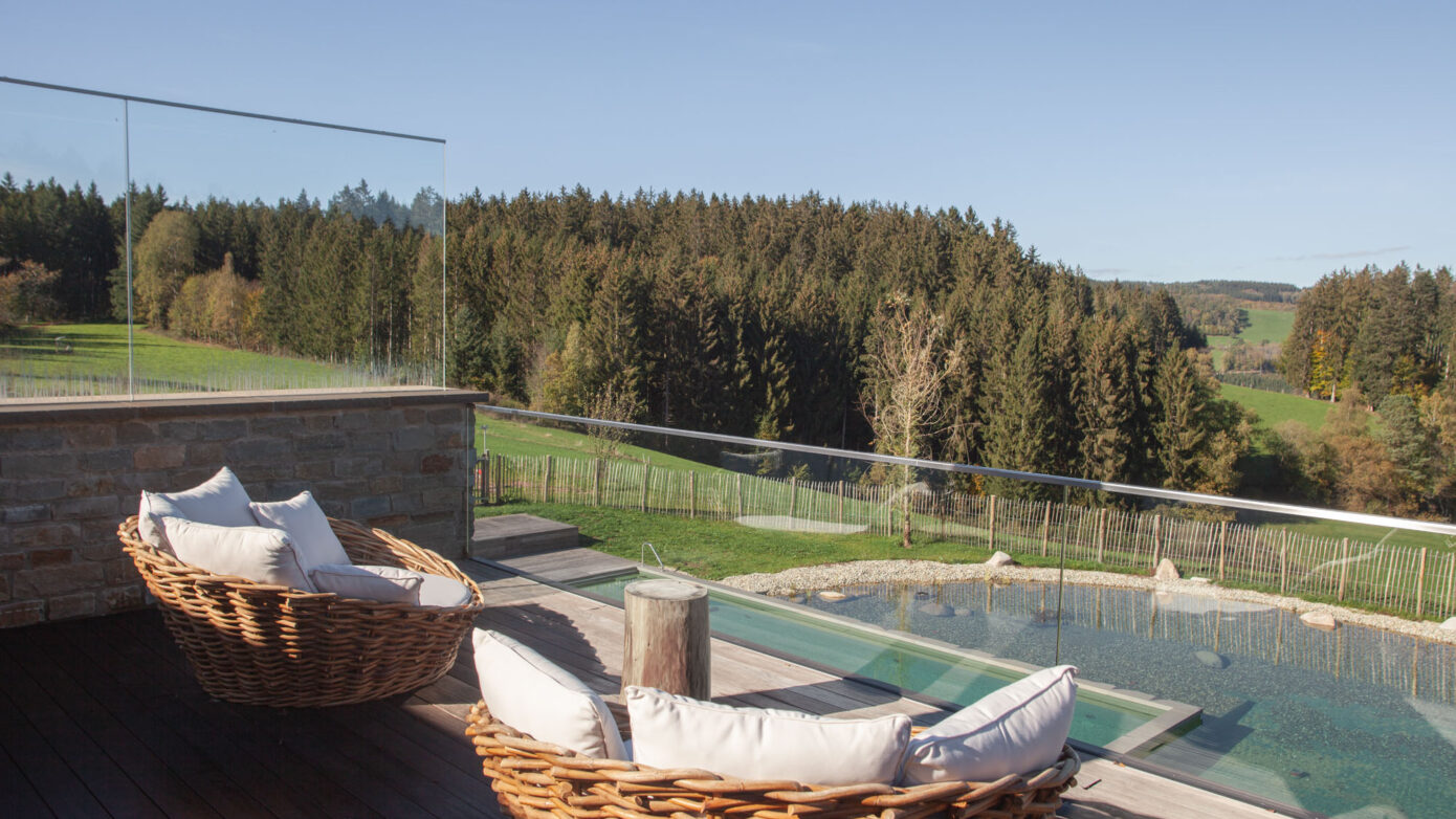 Gemütliche Sitzecke mit Blick auf Natur und Pool auf Terrasse im Grünen.