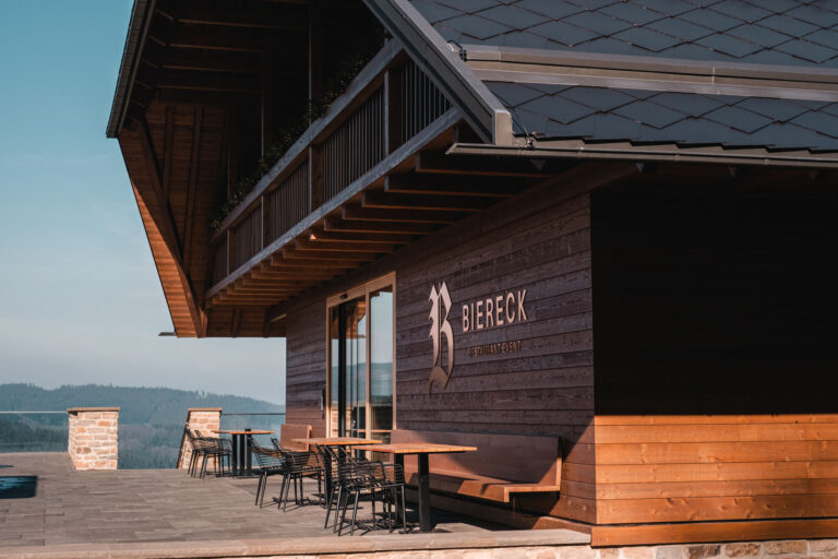 Holzrestaurant "Biereck" mit Terrasse und Blick auf die Berge.