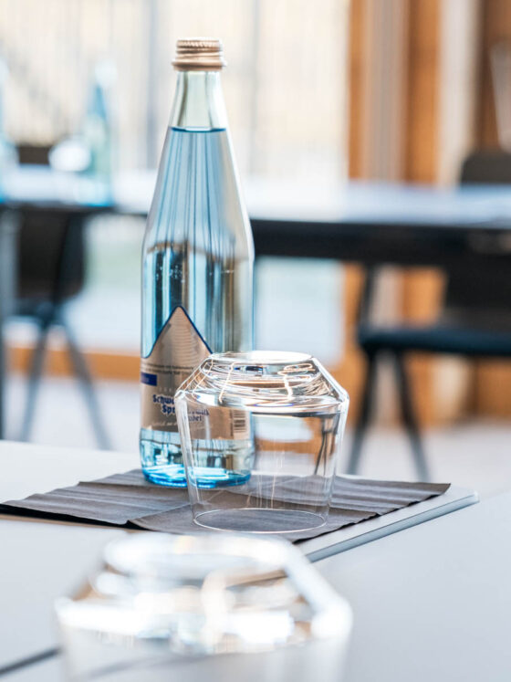Wasserflasche und Glas auf einem Tisch im modernen Restaurant.