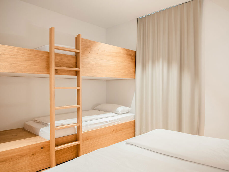 Modernes Schlafzimmer mit Etagenbett und weißen Vorhängen.