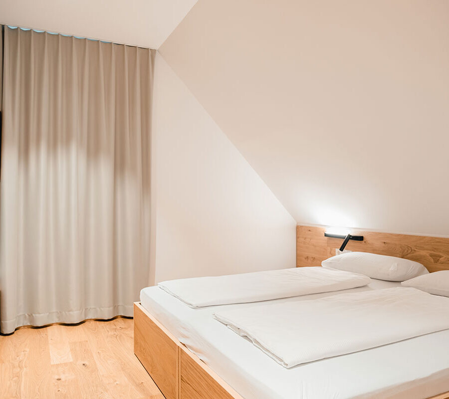 Modernes Schlafzimmer mit Doppelbett, Holzdekoration und Vorhängen.