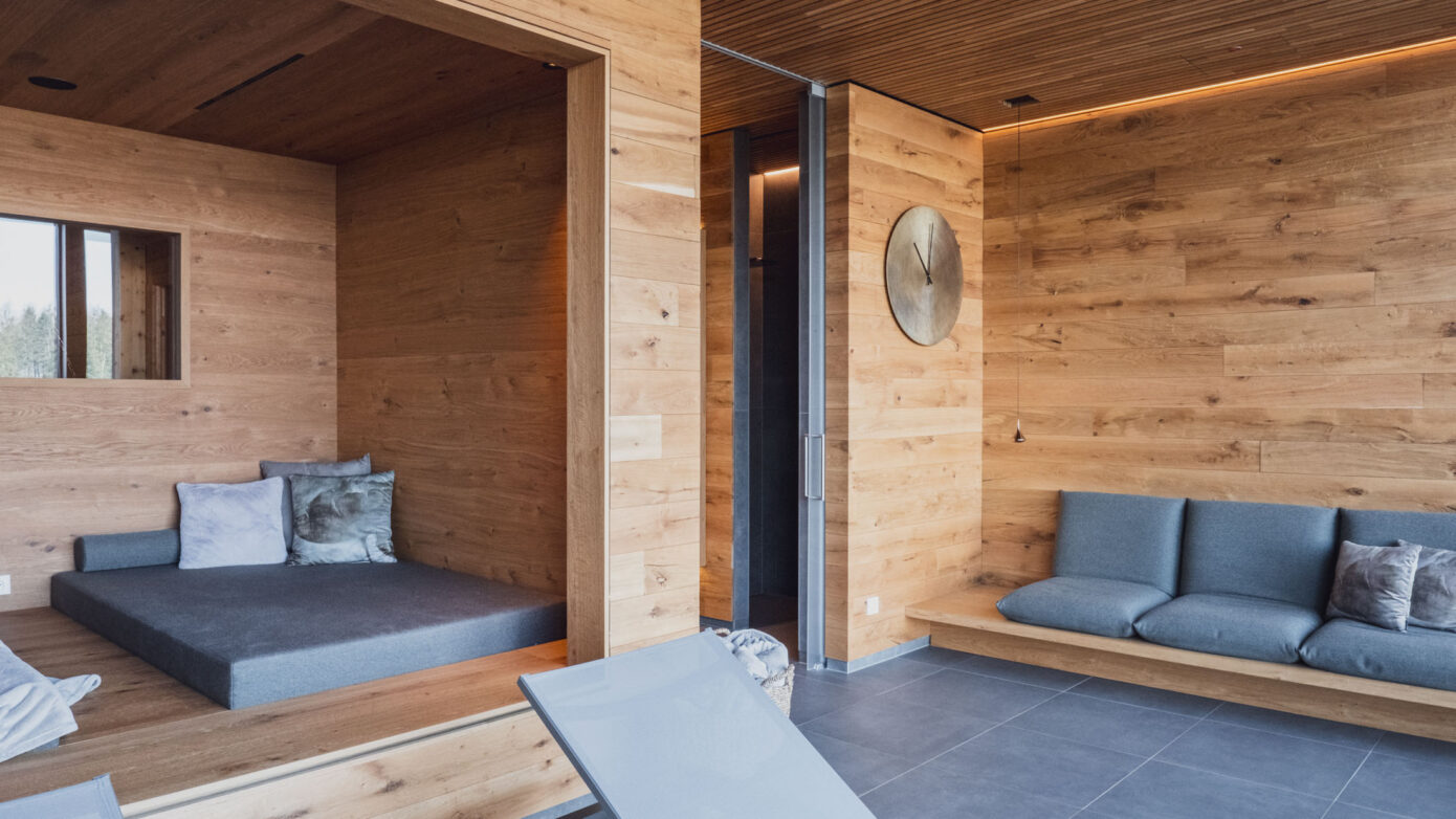 Moderner Holz-Wohnraum mit Sofa, Sitzbank und Relaxliege, stilvoll und gemütlich gestaltet.