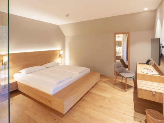 Modernes Hotelzimmer mit Doppelbett, Holzmöbeln und Flachbildfernseher.