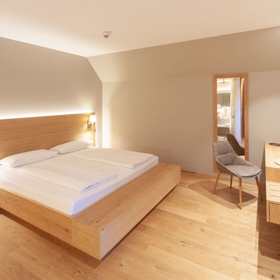 Modernes Hotelzimmer mit Doppelbett, Holzmöbeln und Flachbildfernseher.