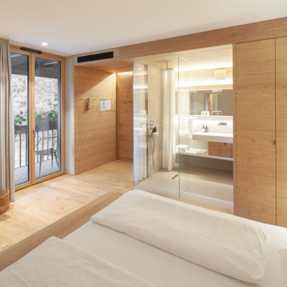 Modernes Hotelzimmer mit Holzdesign, Balkon und offenem Badbereich.