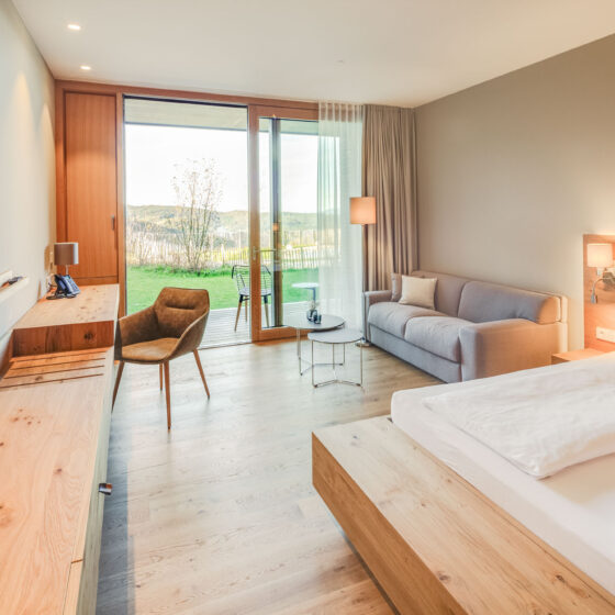Modernes Hotelzimmer mit Blick auf grünen Garten und Natur, komfortabel eingerichtet.