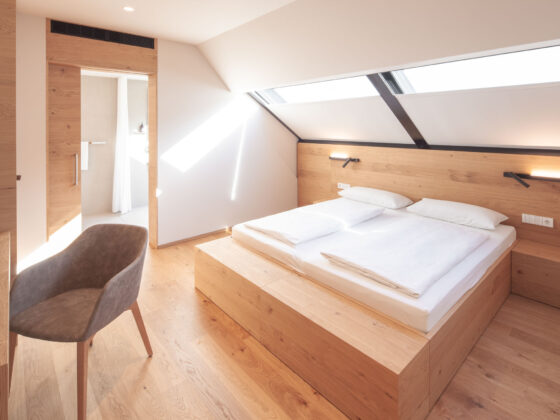 Modernes Schlafzimmer mit Holzdekor, Doppelbett und Dachfenstern für viel Tageslicht.