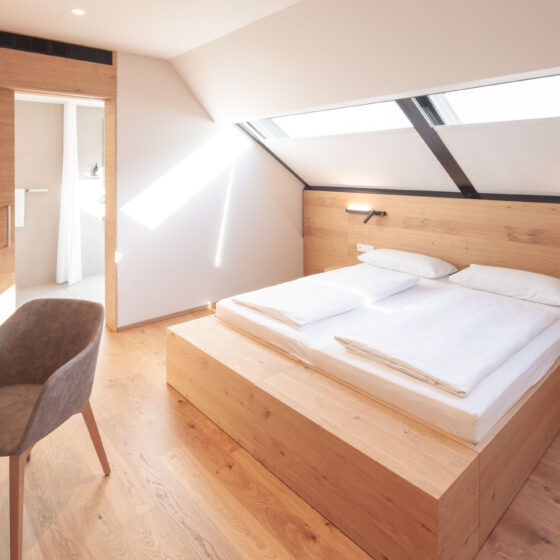Modernes Schlafzimmer mit Holzdekor, Doppelbett und Dachfenstern für viel Tageslicht.