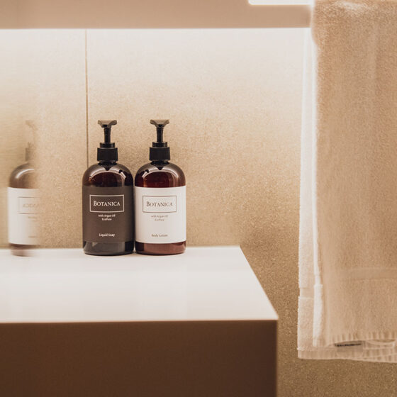 Badezimmer mit Botánica Pflegeprodukten, Handtuch und moderner Wandgestaltung.