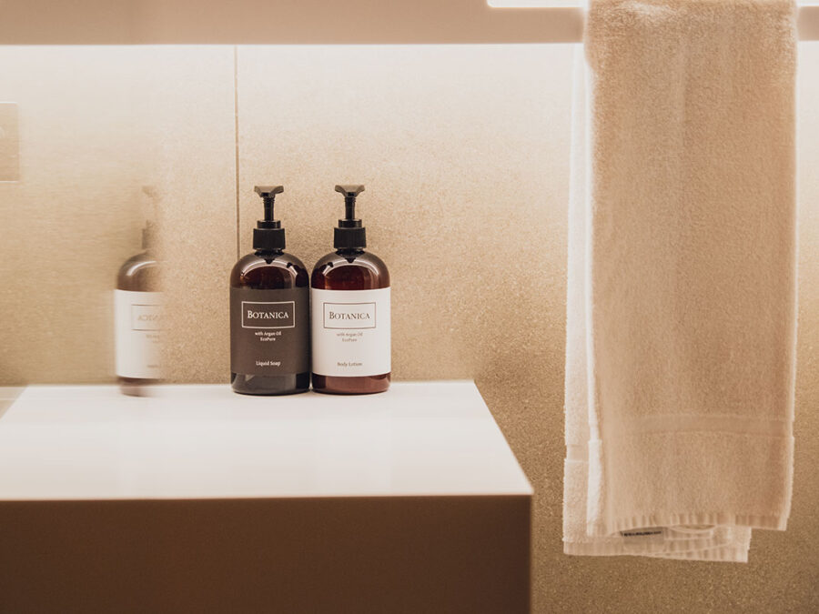 Badezimmer mit Botánica Pflegeprodukten, Handtuch und moderner Wandgestaltung.