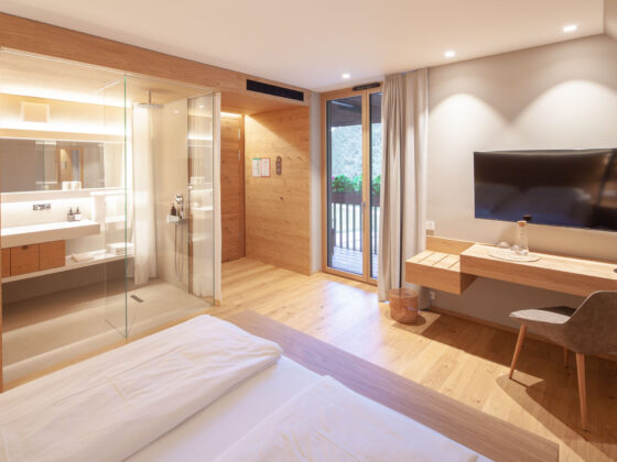 Modernes Hotelzimmer mit offener Dusche, Balkon, Flachbildfernseher und Holzdekoration.