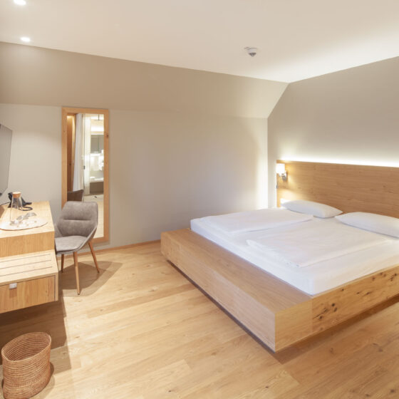Modernes Hotelzimmer mit Doppelbett, Holzmöbeln und gemütlicher Atmosphäre.