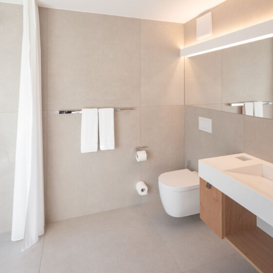 Modernes Badezimmer mit Dusche, Waschbecken und Spiegel in hellem Design.