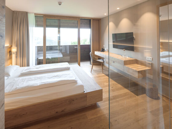 Modernes Hotelzimmer mit Doppelbett, Balkon und Flachbildfernseher.