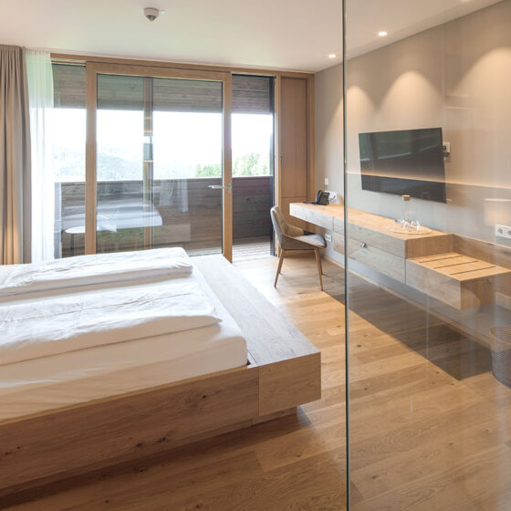 Modernes Hotelzimmer mit Doppelbett, Balkon und Flachbildfernseher.