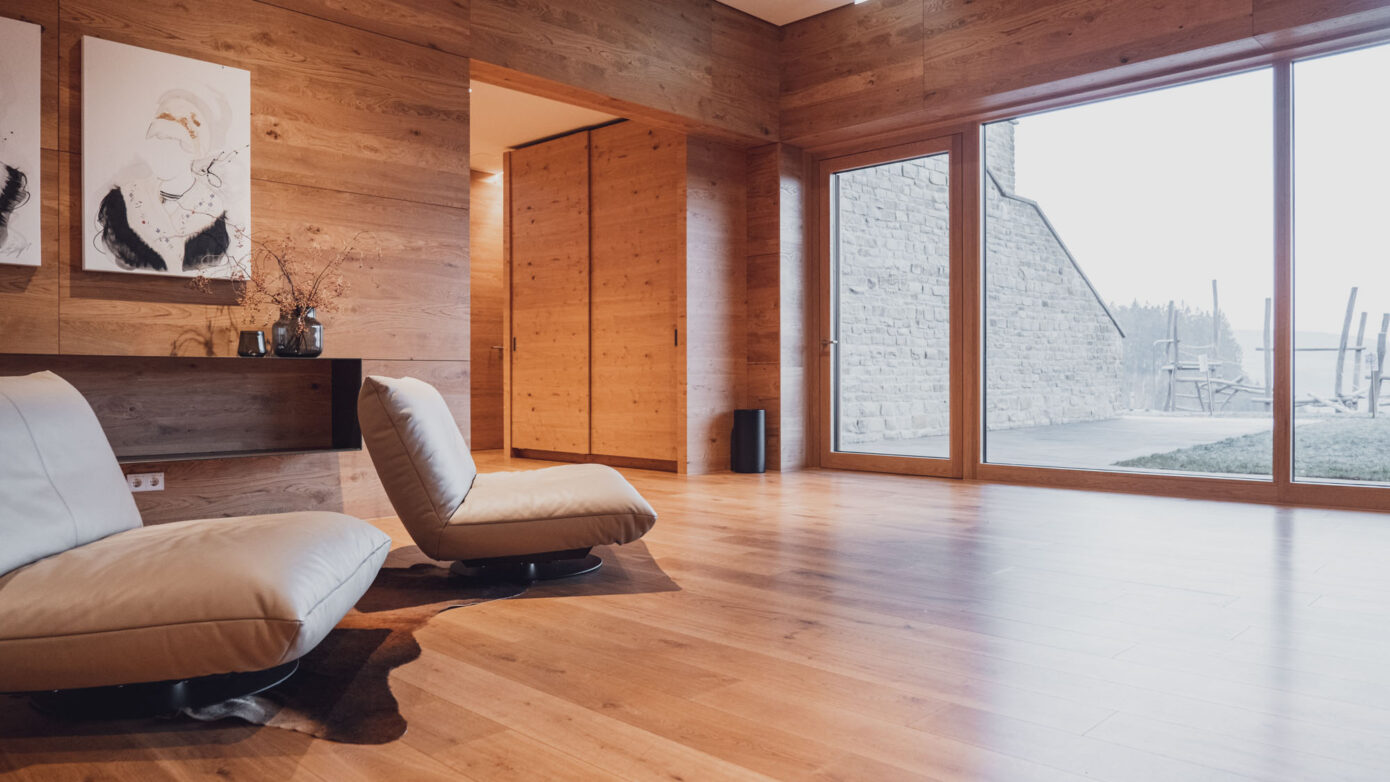 Modernes Wohnzimmer mit Holzdekor, großen Fenstern und minimalistischer Einrichtung.