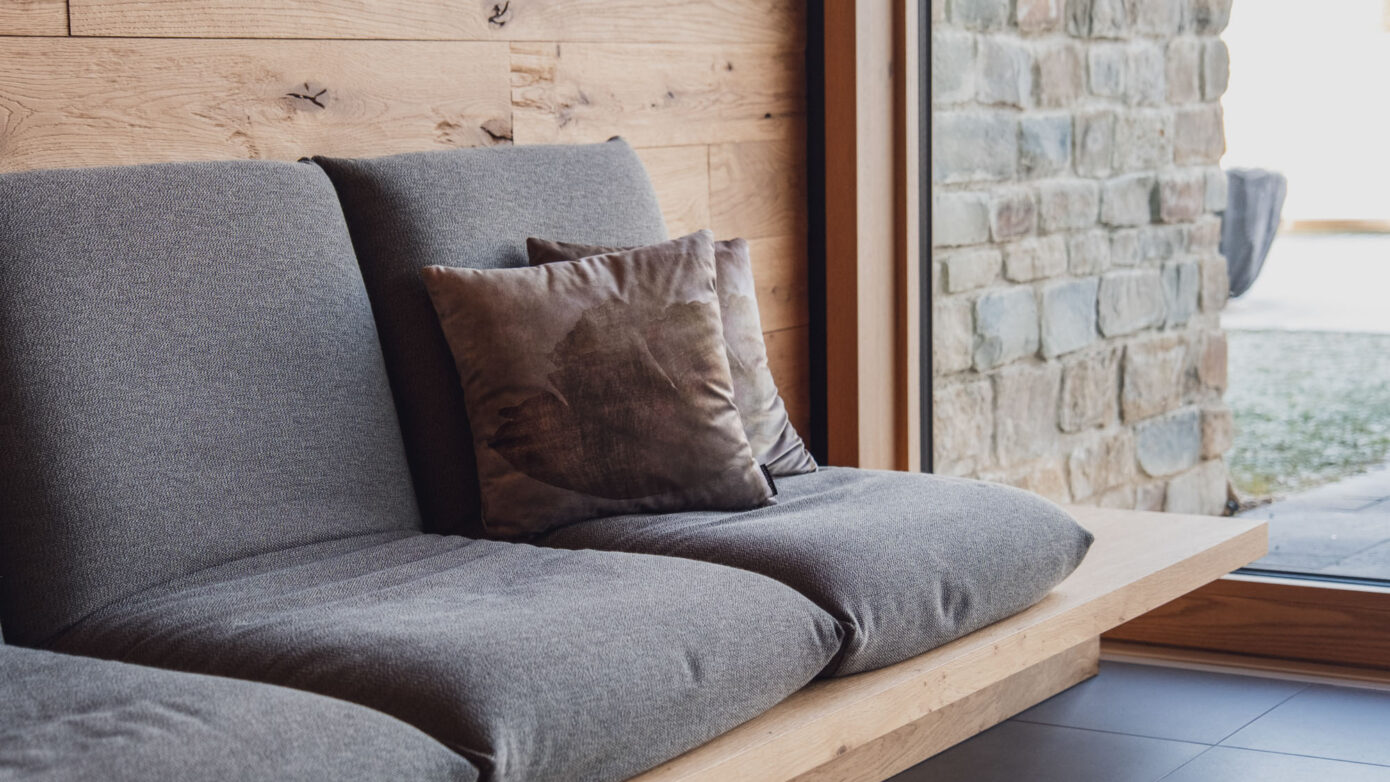 Gemütliche Sitzecke mit grauem Sofa, Kissen und Holz-Wand in modernem Interior.