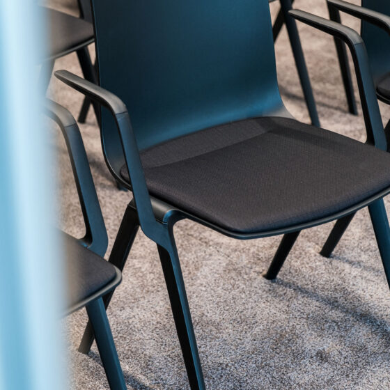 Leere blaue und schwarze Sitzstühle in einem Konferenzraum.