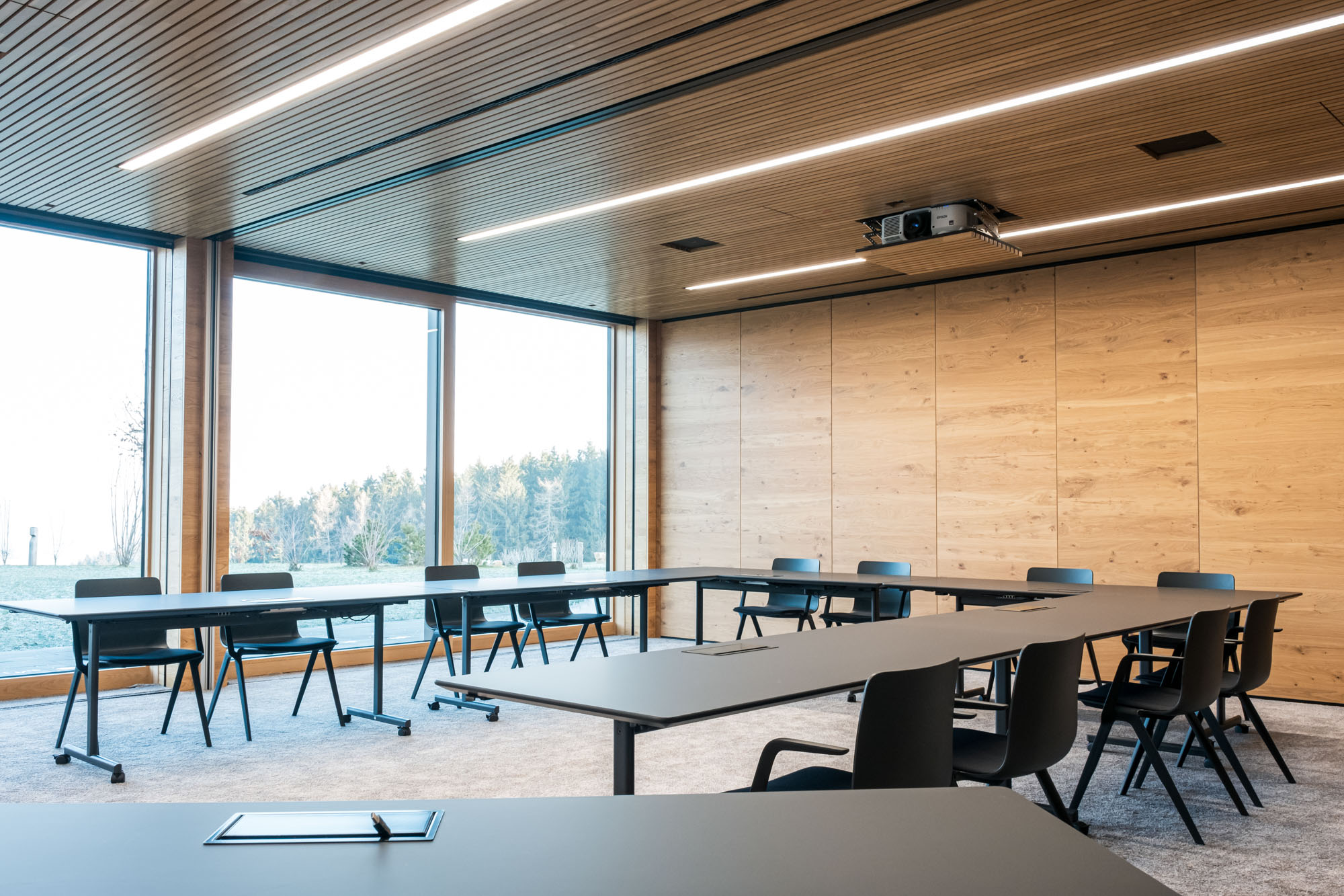 Moderner Konferenzraum mit Holzpaneelen und großen Fenstern.