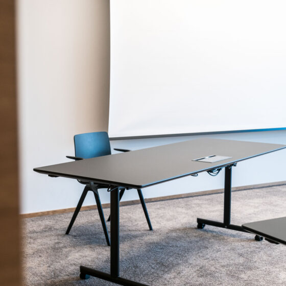 Leerer Konferenzraum mit Tisch, Stuhl und Whiteboard.