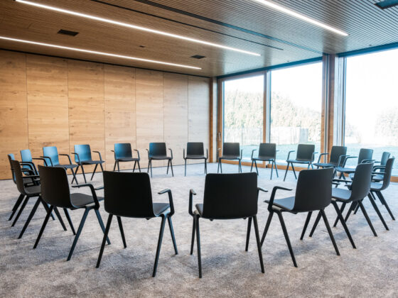 Leerer Sitzkreis in modernem Konferenzraum mit Holzdecke und großen Fenstern.