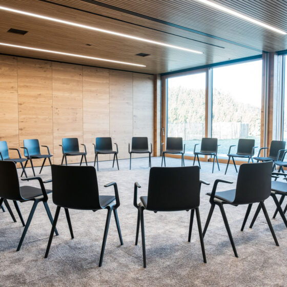 Leerer Sitzkreis in modernem Konferenzraum mit Holzdecke und großen Fenstern.