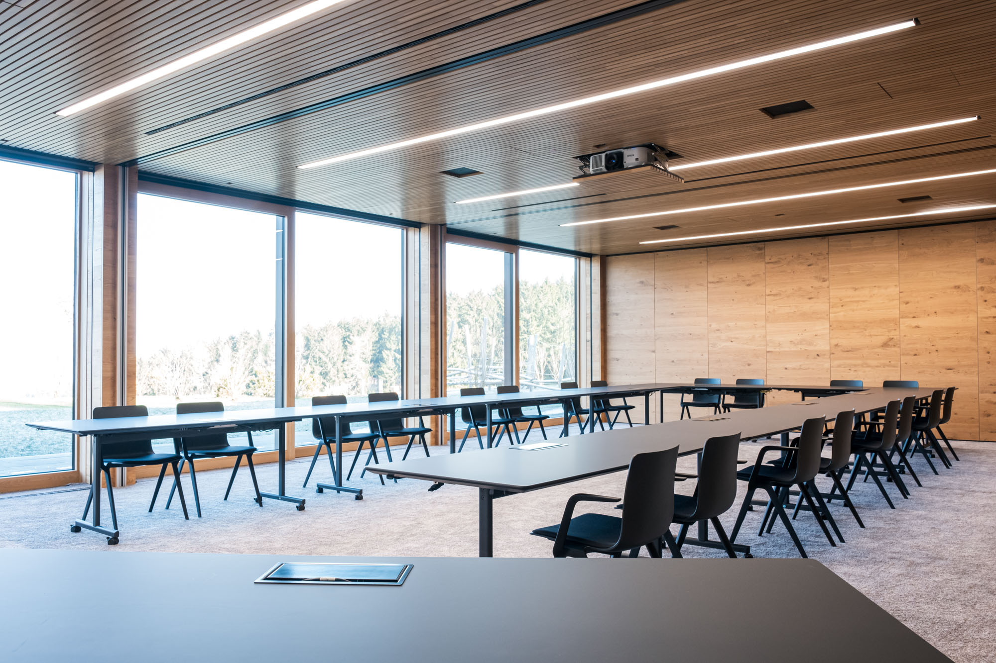 Moderne, leeres Konferenzraum mit großen Fenstern, Tischen und Stühlen.