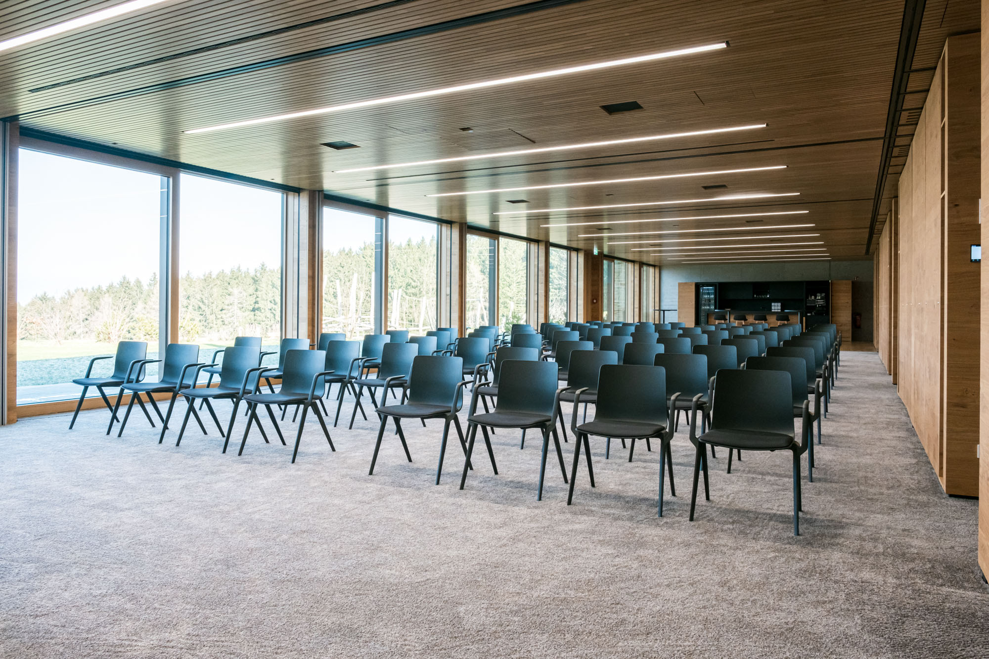 Moderne, helle Konferenzraum mit Stühlen und großen Fensterblick ins Grüne.