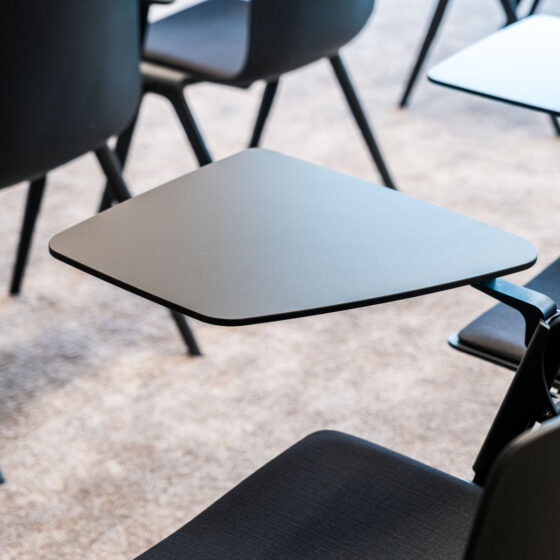 Moderne schwarze Konferenzstühle mit abnehmbaren Tischen in einem Besprechungsraum.