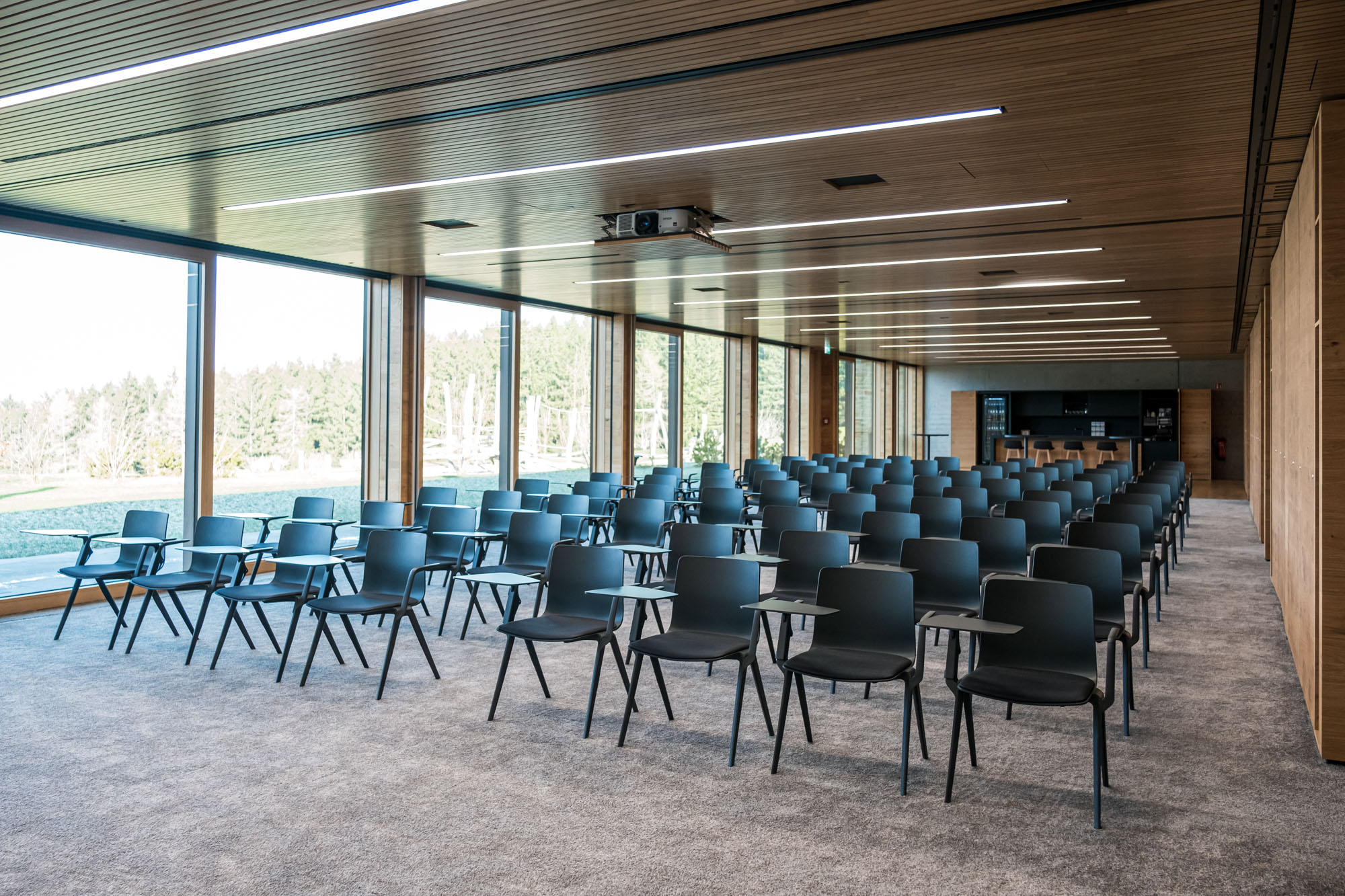 Moderne Konferenzraum mit schwarzen Stühlen und großen Fensterfronten.
