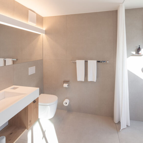 Modernes, minimalistisches Badezimmer mit Dusche, WC und Waschbecken in hellem Design.