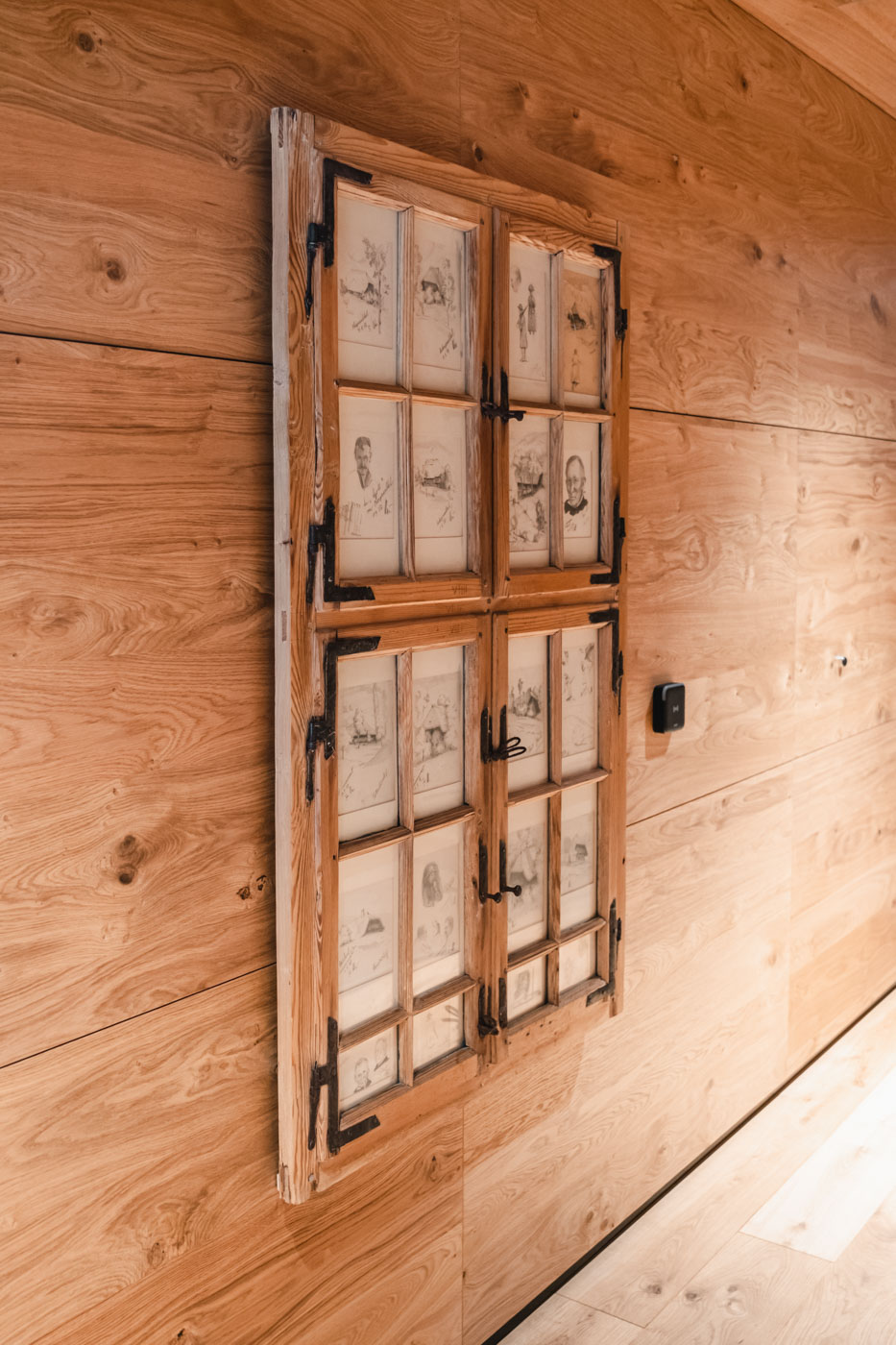 Antikes Fenster mit Holzrahmen und Bildern hinter Glas an Holz-Wand montiert.