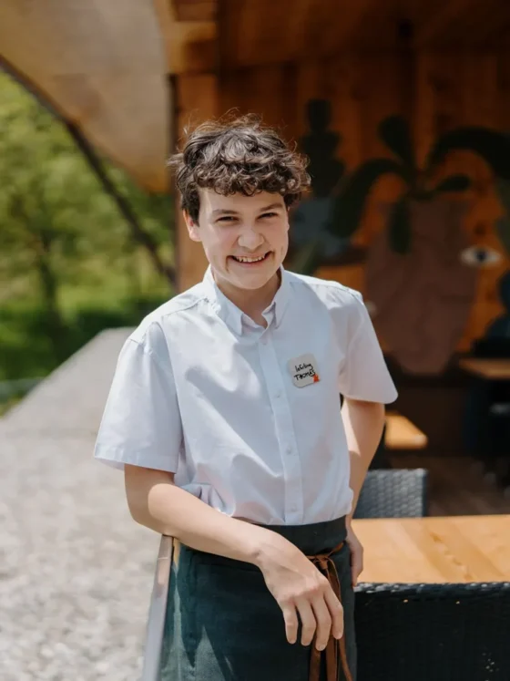 Junge Kellnerin in Weißes Hemd und schwarze Schürze, lächelnd im Restaurant.