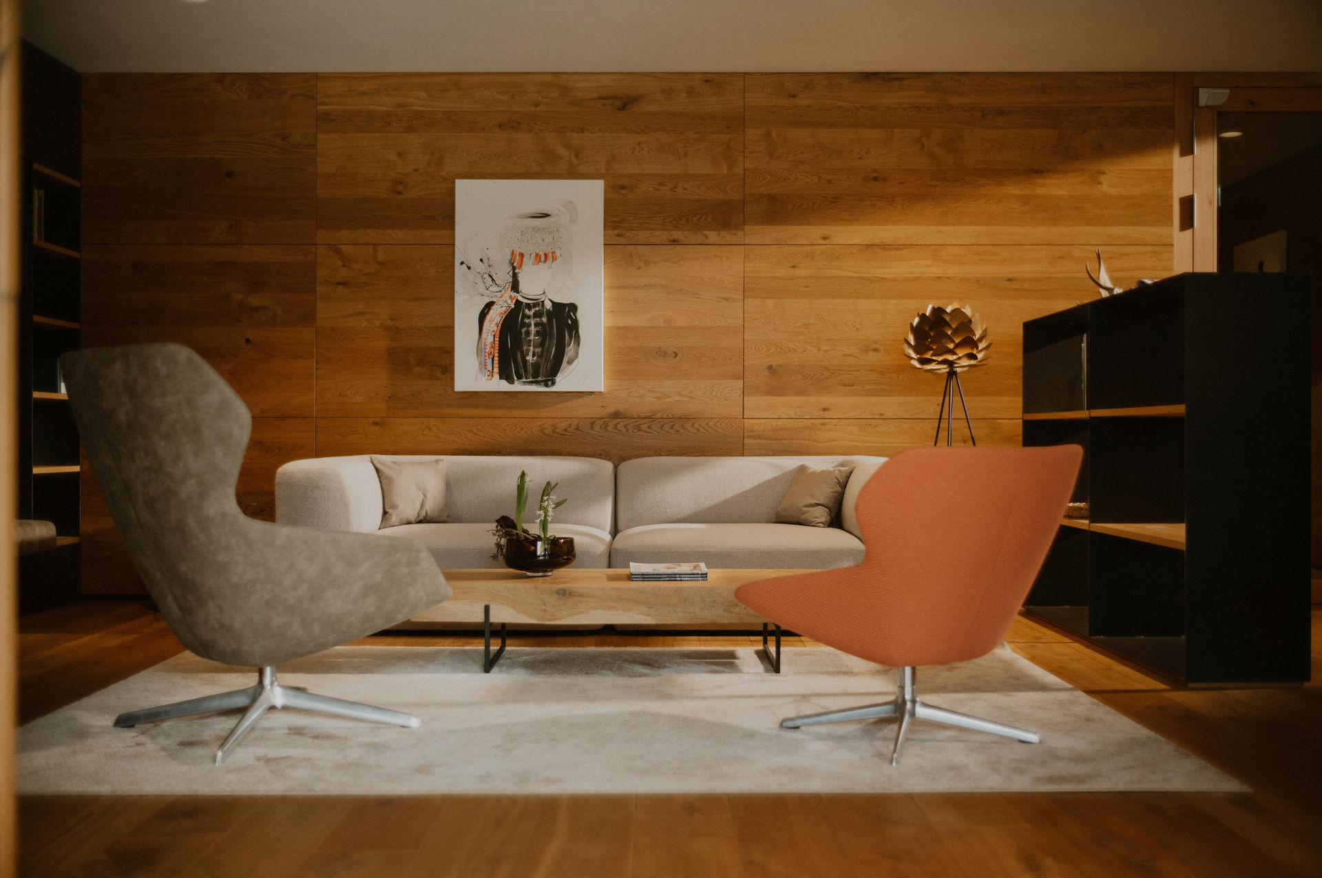 Moderner Wohnzimmerbereich mit Sofa, Sessel und Holzdekorwand.