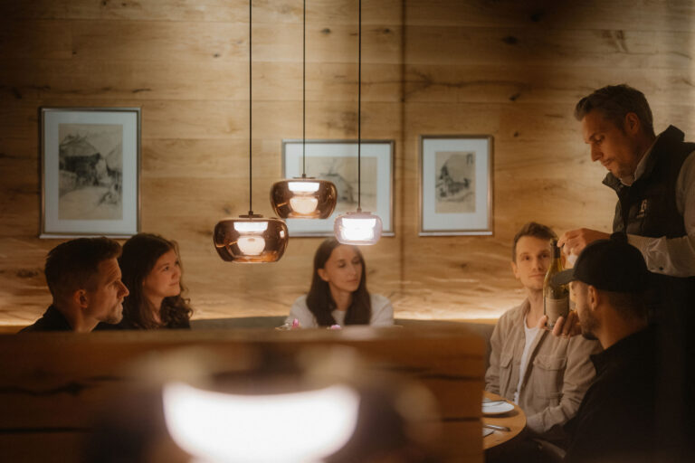 Gemütliches Abendessen in rustikalem Holzrestaurant mit modernen Lampen und entspanntem Ambiente.