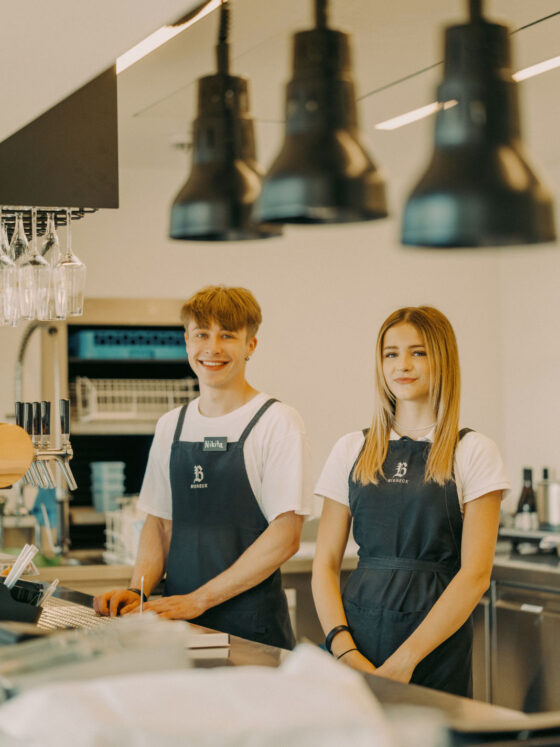 Zwei freundliche Baristas in Schwarz-Weißen Uniformen hinter der Theke.